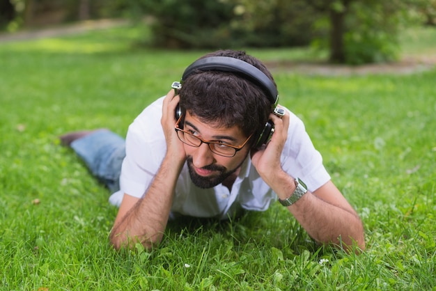 Jonge vrolijke man luisteren muziek in het park