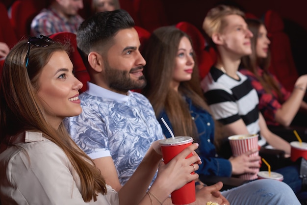 Jonge vrolijke mensen glimlachend vreugdevol ontspannen in de bioscoop kijken naar komedie film vrienden vriendschap entertainment activiteit vrije tijd plezier positiviteit levensstijl.