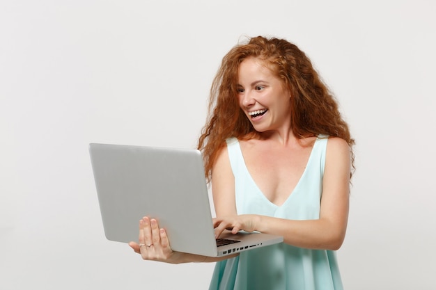 Jonge vrolijke roodharige vrouw meisje in casual lichte kleding poseren geïsoleerd op een witte muur achtergrond studio portret. Mensen levensstijl concept. Bespotten kopie ruimte. Bedrijf werken op laptop pc-computer.