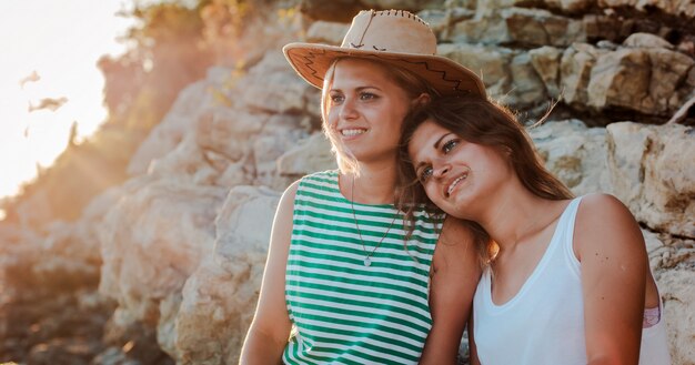 jonge vrolijke vrouwen in hipstershoeden op een rots aan de kust van de zee.