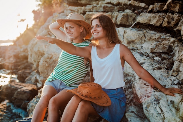 jonge vrolijke vrouwen in hipstershoeden op een rots aan de kust van de zee.