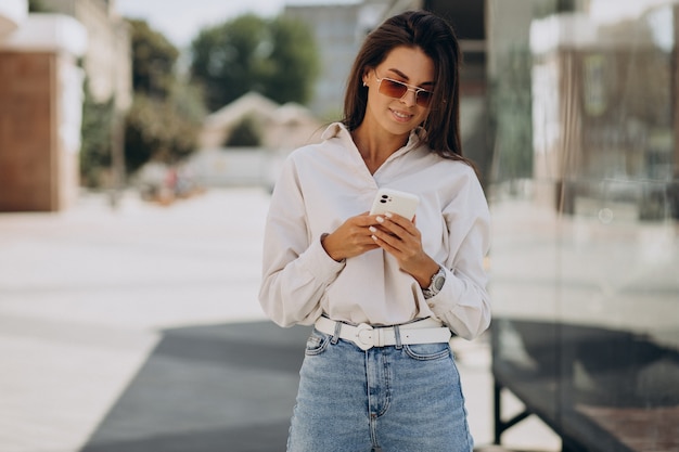 Jonge vrouw aan de telefoon buiten de straat