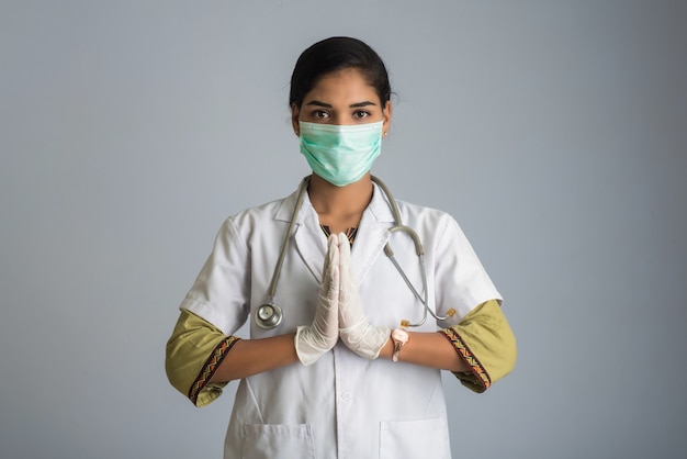 Jonge vrouw Arts die Namaste doet wegens het uitbreken van COVID-19. Nieuwe begroeting om de verspreiding van coronavirus te voorkomen in plaats van te begroeten met een knuffel of handdruk.