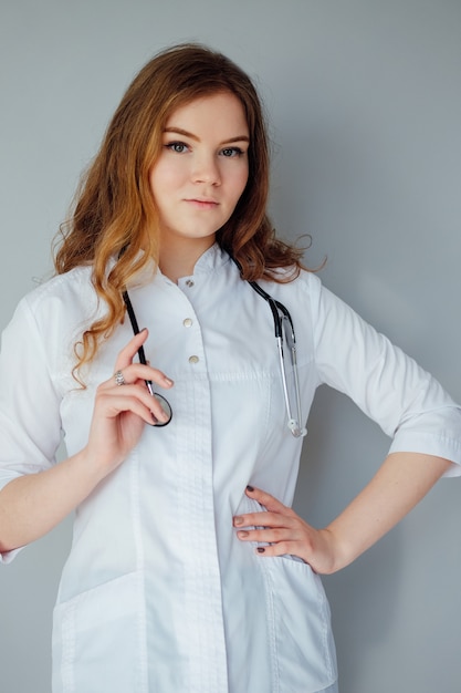 Foto jonge vrouw arts in een witte jas en een medisch masker. het medicijn