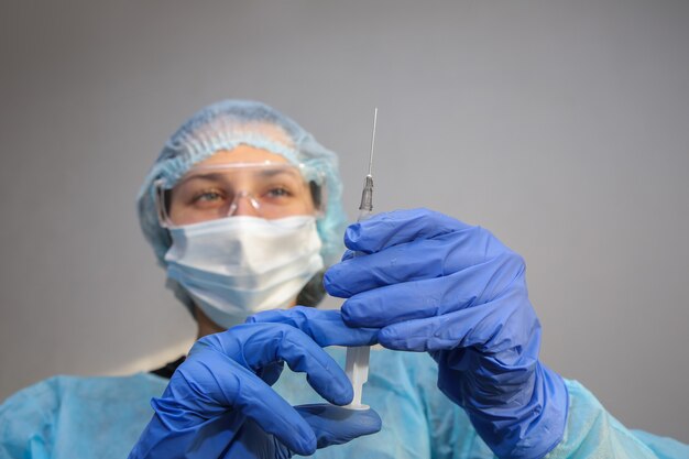 jonge vrouw arts-verpleegkundige in een beschermend masker met een spuit in haar hand