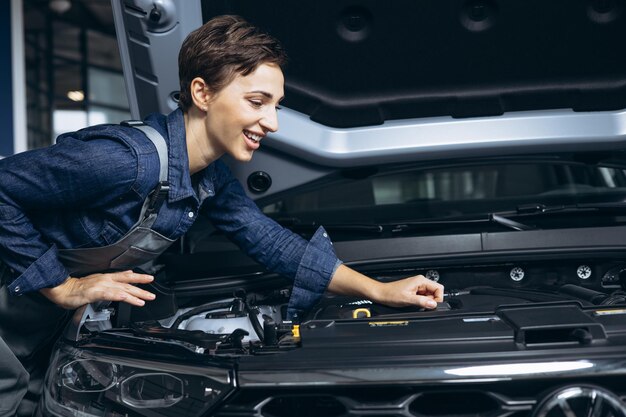 Jonge vrouw automonteur die auto controleert bij autoservice