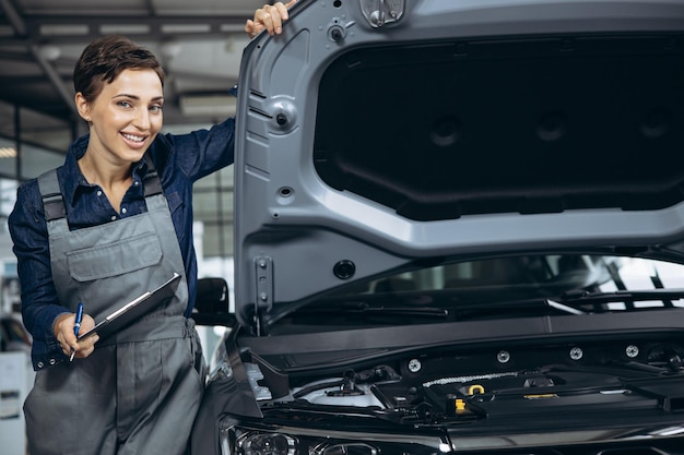 Jonge vrouw automonteur die auto controleert bij autoservice