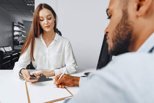 Jonge vrouw autoverkoper die contract toont aan een paar autokopers