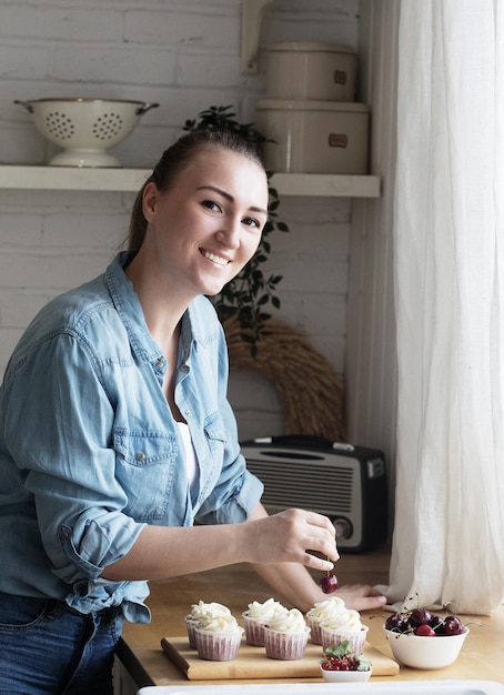 Jonge vrouw banketbakker versiert cupcakes