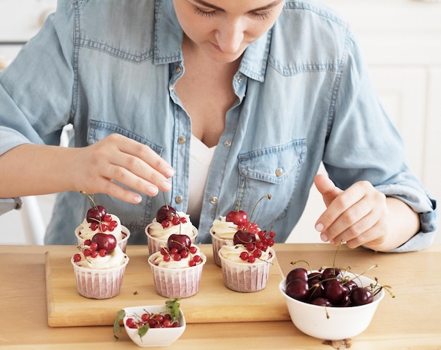 Foto jonge vrouw banketbakker versiert cupcakes