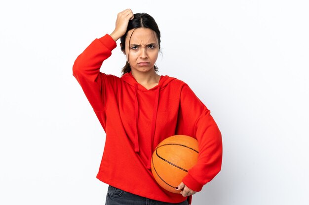 Jonge vrouw basketbal spelen over geïsoleerde witte achtergrond met een uitdrukking van frustratie en niet begripvol
