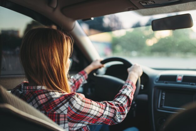 Jonge vrouw beginner autorijden, achteraanzicht