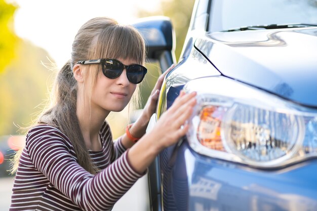 Foto jonge vrouw behandeling van nieuwe auto bij dealer verkoop winkel voor aankoop.