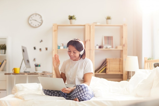 Jonge vrouw bellen via videochat op bed