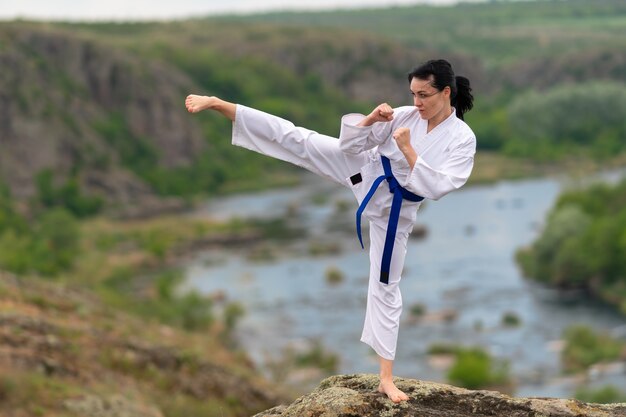 Jonge vrouw beoefenen van kickboksen buiten in de natuur balanceren