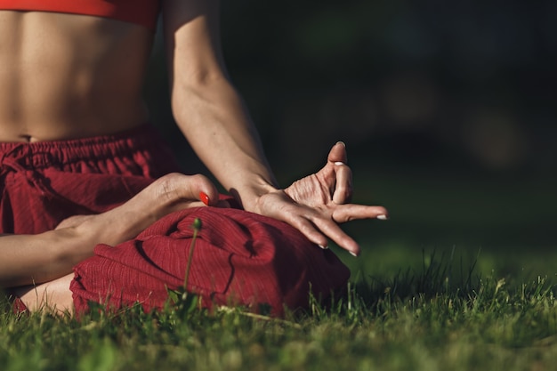 Jonge vrouw beoefenen van yoga buitenshuis. Het wijfje mediteert openlucht in het park van de de zomerstad.