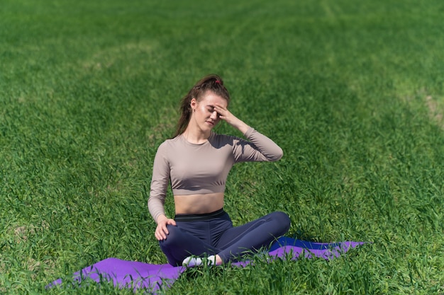 Jonge vrouw beoefenen van yoga op het veld