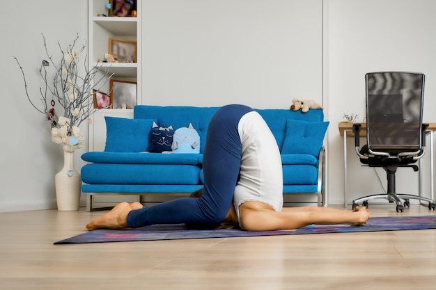 Jonge vrouw beoefenen van yoga thuis, ploeg pose