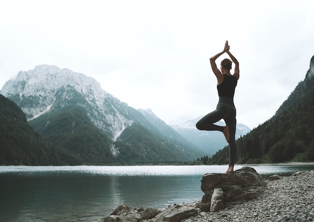 Jonge vrouw beoefent yoga bij bergmeer Meisje doet yoga op de natuur Gezonde levensstijl