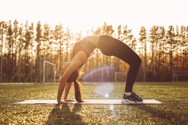 Jonge vrouw beoefent yoga in een stadion