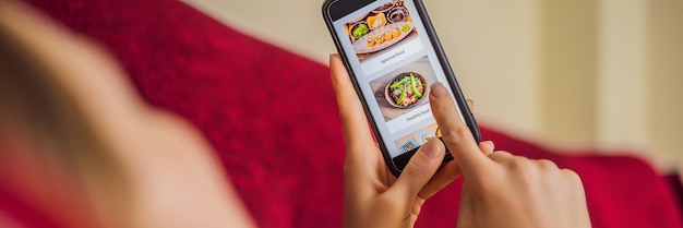 Jonge vrouw bestelt lunch online met behulp van een smartphone BANNER LONG FORMAT