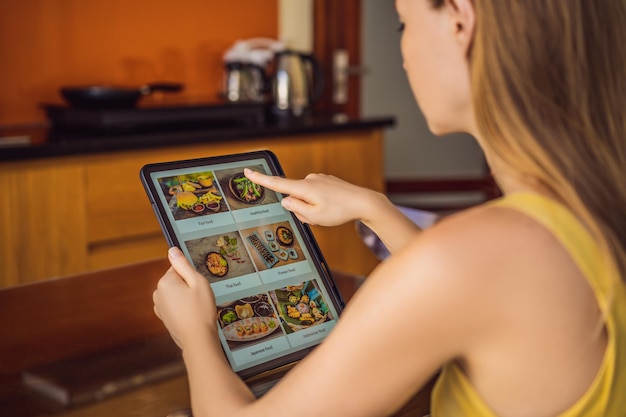 Jonge vrouw bestelt lunch online met behulp van een tablet