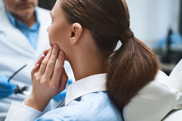 Jonge vrouw bezoekt mannelijke tandarts in modern kantoor vanwege gebitsproblemen