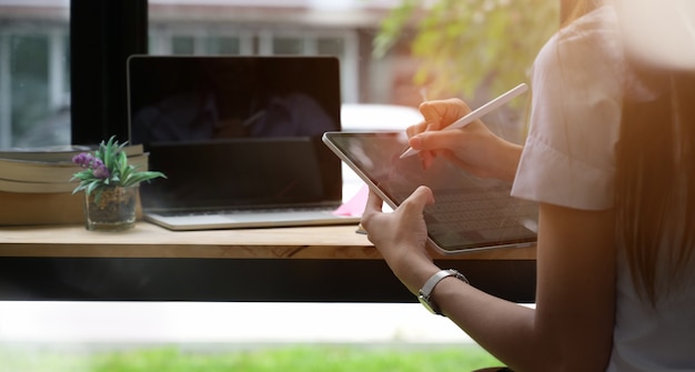 Jonge vrouw bij bibliotheek die een tablet gebruikt