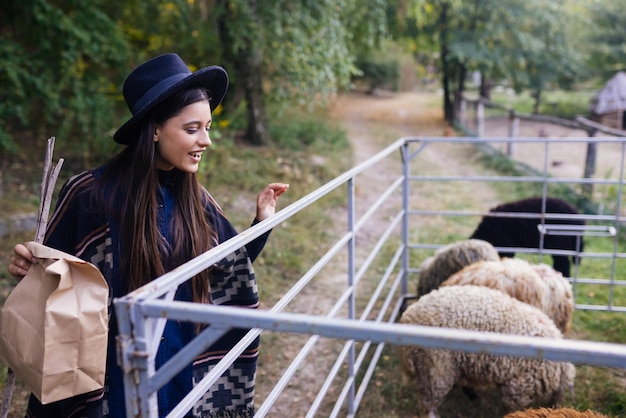 Jonge vrouw bij een hok met schapen op een boerderij