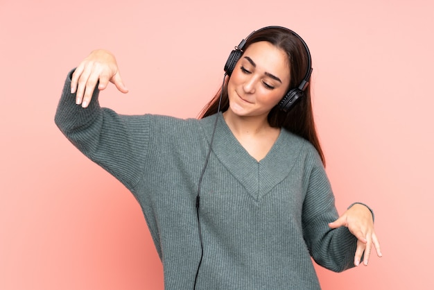 Jonge vrouw bij het roze het luisteren muziek en dansen