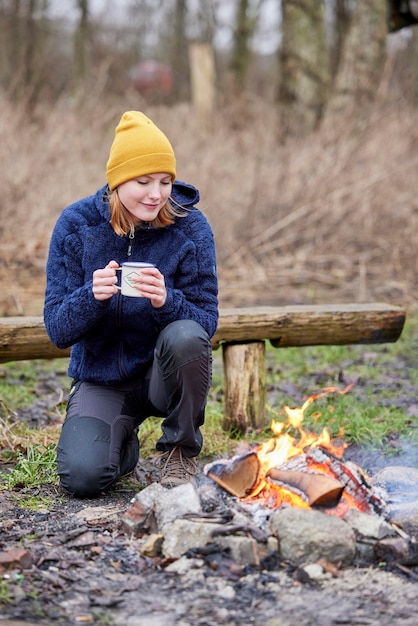 Jonge vrouw bij vuur met warme chocolademelk in de hand