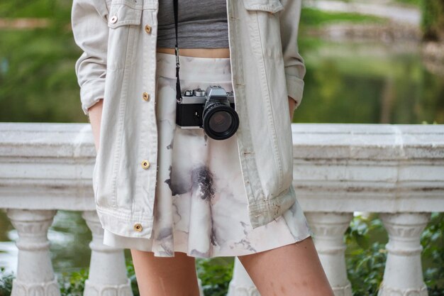 Jonge vrouw bijsnijden met retro camera in het park