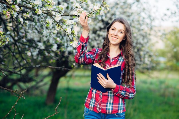 Jonge vrouw binnen met boek in een bloeiende tuin