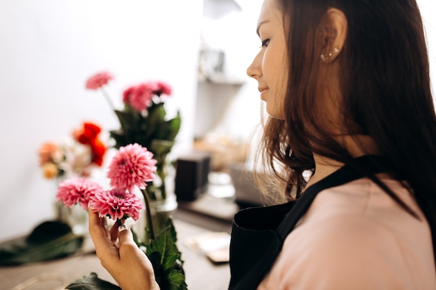 Jonge vrouw bloemist raakt met haar hand verse roze chrysanten.