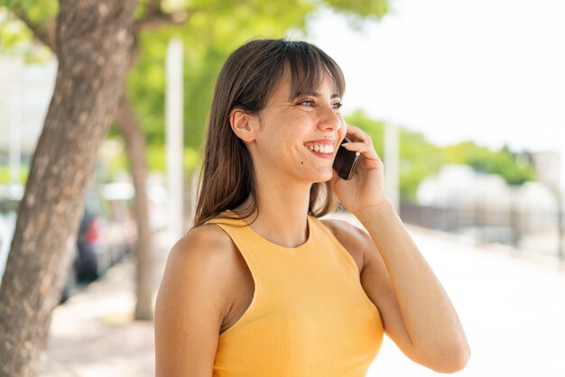 Jonge vrouw buiten een gesprek aan het voeren met de mobiele telefoon