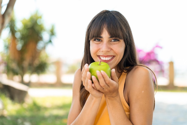 Jonge vrouw buiten met een appel in de hand