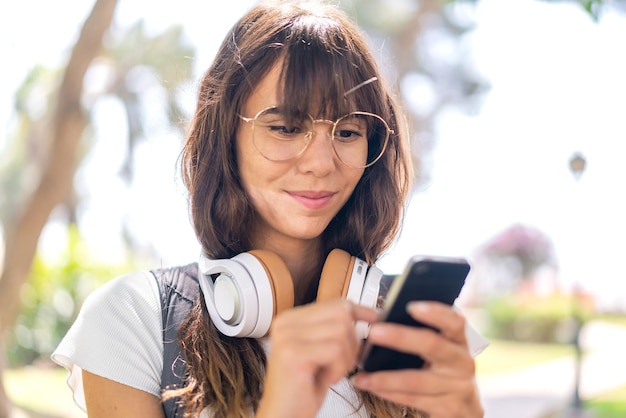 Jonge vrouw buitenshuis met behulp van mobiele telefoon