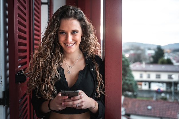 Jonge vrouw chatten met haar mobiele telefoon op het terras