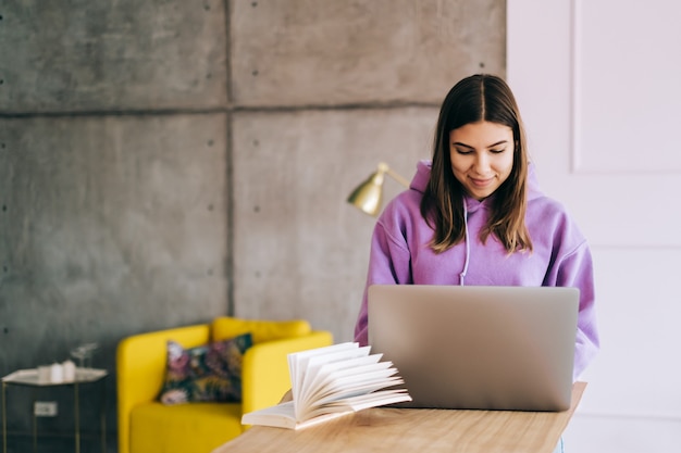 Jonge vrouw college student studeren met laptop, verre voorbereiding voor proefexamen, schrijven essay huiswerk thuis, verre onderwijs concept.