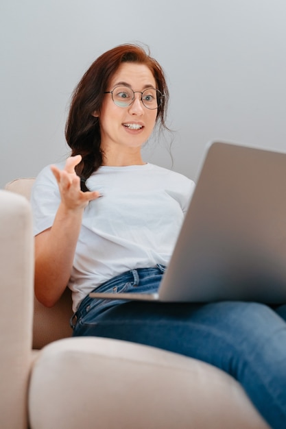 Jonge vrouw communiceert emotioneel met gebaren via videocommunicatie met vrienden