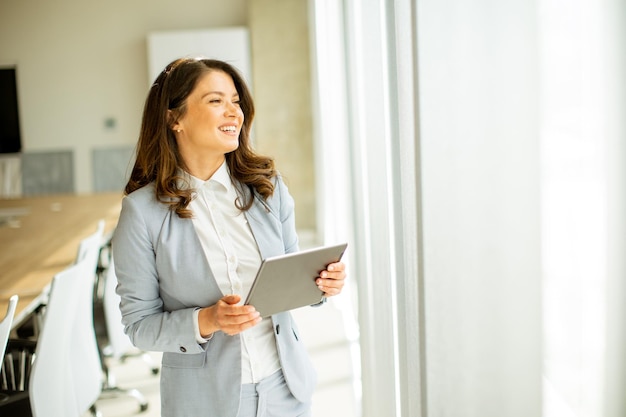 Jonge vrouw die aan digitale tablet werkt bij het loket