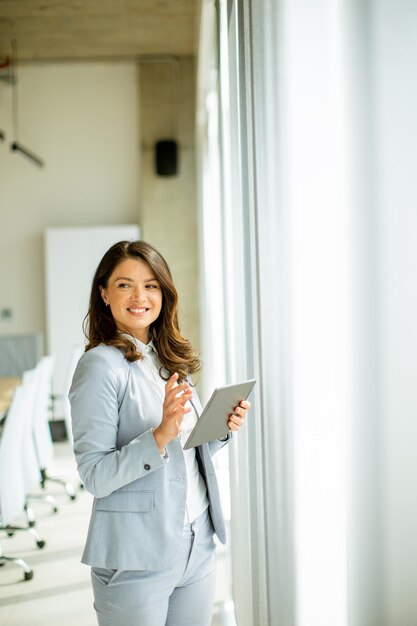 Jonge vrouw die aan digitale tablet werkt bij het loket