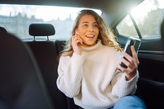 Jonge vrouw die aan het bellen is op de achterstoel van de auto Business technology blogging concept