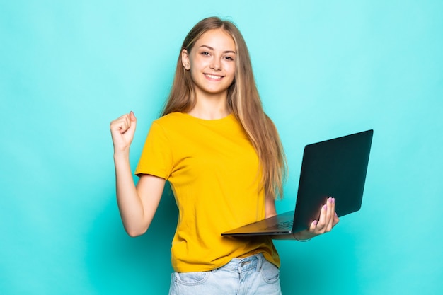 Jonge vrouw die aan laptop met win gebaar poseren geïsoleerd op turkooizen muur werkt