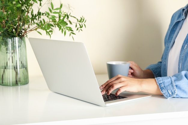 Jonge vrouw die aan laptop werkt en koffie drinkt