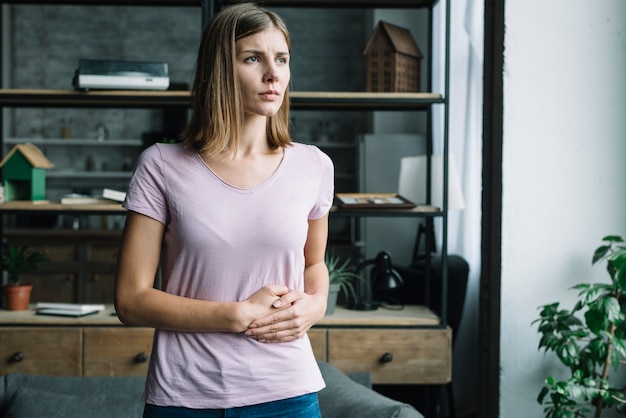 Jonge vrouw die aan maagpijn lijdt