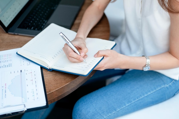 Jonge vrouw die aantekeningen maakt in een notitieboekjeclose-up