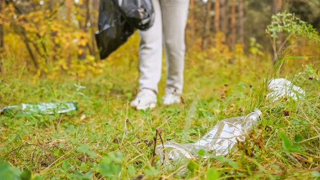 Jonge vrouw die afval in het bos verzamelt.