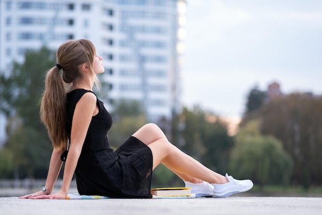 Jonge vrouw die alleen op straat in de stad zit en buiten geniet van een warme zomerdag Welzijn en ontspannen op frisse lucht concept