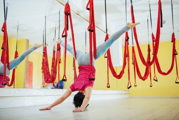 Jonge vrouw die antigravity yogaoefeningen maakt